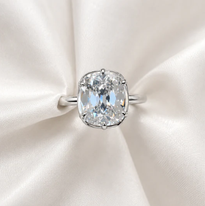 A cushion-cut diamond solitaire ring from Jwalin Jewels resting on white satin